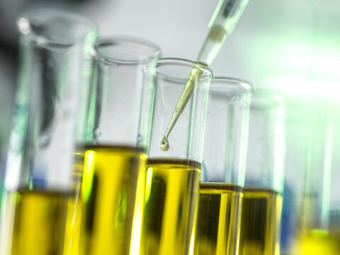 Close-up of yellow liquid being added to test tubes with a pipette in a laboratory