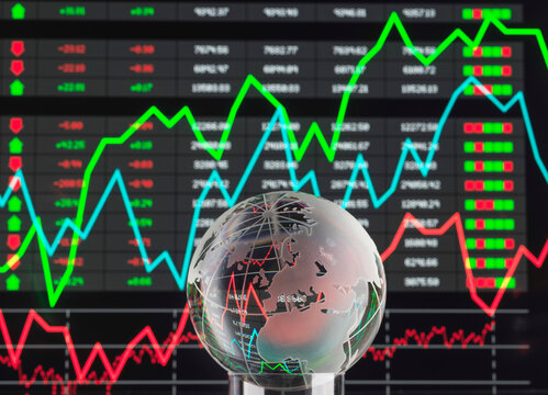 Glass globe in front of a fluctuating stock market graph display with vibrant colors.