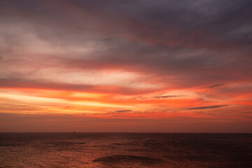 Obraz premium Vibrant sunset over a calm ocean with dramatic clouds in the sky. Vung Tau, Vietnam