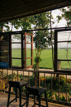 Open windows reveal a serene view of lush green fields and trees under a partly cloudy sky. Hoi An, Vietnam
