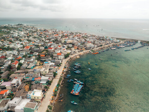 Aerial view of a coastal town with colorful boats and clear blue ocean waters. Ly Son island, Vietnam