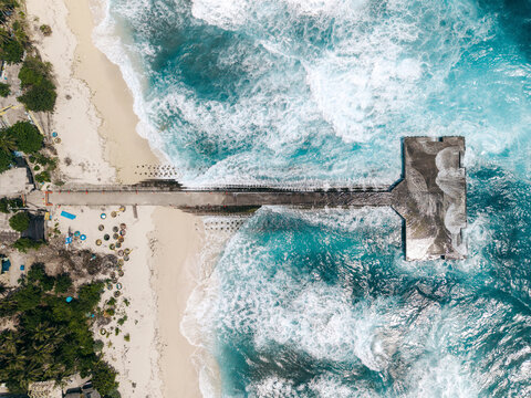Aerial view of a pier extending into the turquoise ocean surrounded by white sandy beaches. Ly Son island, Vietnam