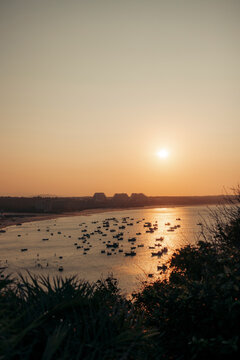 Tranquil sunset over a bay with numerous small boats floating on the water.