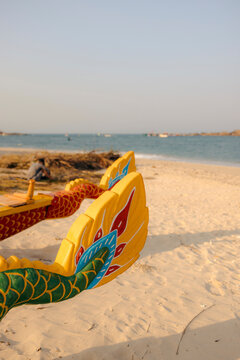 Colorful dragon boat on a sandy beach with a calm sea and clear sky in the background.