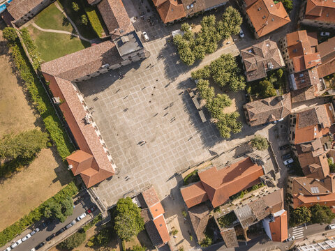 Aerial view of a town square surrounded by buildings and trees on a sunny day.