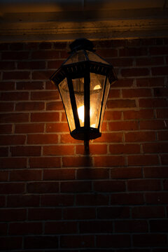 Vintage lantern illuminates a brick wall with warm glow at night. Auckland, New Zealand