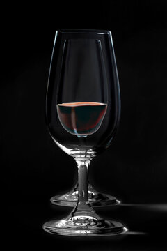 Two wine glasses, one with red wine, elegantly arranged against a dark background.