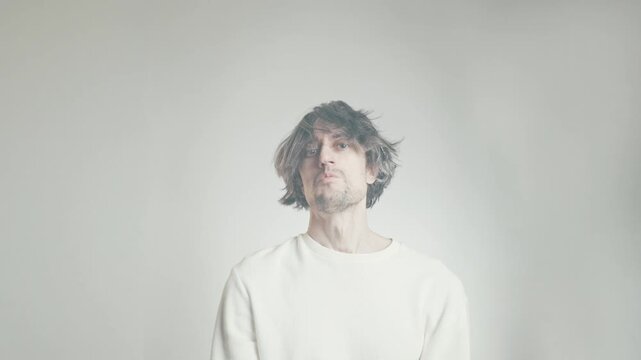 Comical shaggy-haired man giving an arrogant approving nod in close-up studio portrait