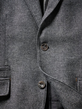 Close-up of a gray textured jacket with buttons and a visible pocket.