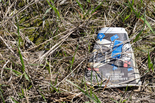 La Tuque, Quebec, 16 May 2026 : A discarded McDonald's McCafe coffee cup lies on the ground among dry grass and green shoots.