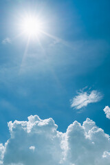 Obraz premium Summer blue sky background, Beautiful sunbeam and bright sunray flare over white clouds.