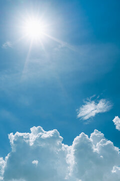 Summer blue sky background, Beautiful sunbeam and bright sunray flare over white clouds.