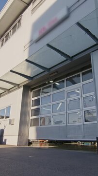 Beginning of the working day in the professional car repair shop, sunlight enters the spacious workshop as the roller doors open.