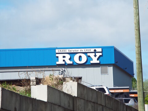 Chelsea,Quebec, Canada &ndash; May 14, 2026: A blue and grey industrial building displays signage for "Crane Service de Grue  ROY", a company offering crane and heating services at 23 Quebec Rte 105.
