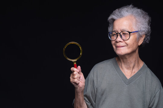 Senior woman holding magnifying glass for vision care