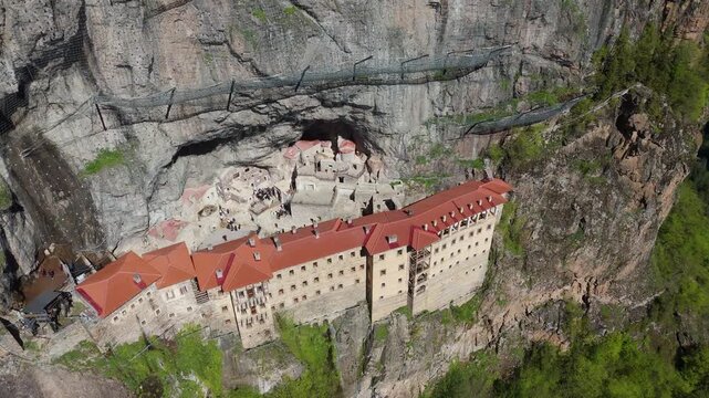 Sumela Monastery nestled among dense green pine woods in Trabzon, Turkey travel destination drone aerial footage