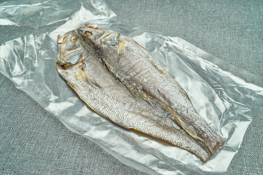 These photos feature premium dried croaker on a gray background. One shows the silver skin, while the other reveals the butterflied interior and clean meat, highlighting hygienic seafood processing.