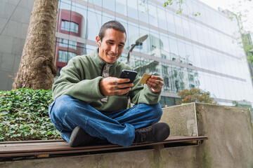 Obraz premium Man shopping online with credit card and smartphone outdoors