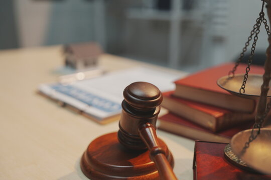 Gavel, scales of justice and law books on a desk in a law office, showing legal research, court work and the idea of justice and balance.