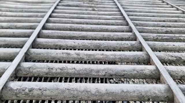Dirty industrial steel grating texture, close up overhead view of heavy duty weathered metal drainage drainage trench cover with geometric patterns