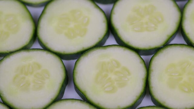 Repeating cucumber slices with vibrant green color and white background. High contrast studio shot showcasing crisp cucumber slices in repeating pattern for healthy food imagery