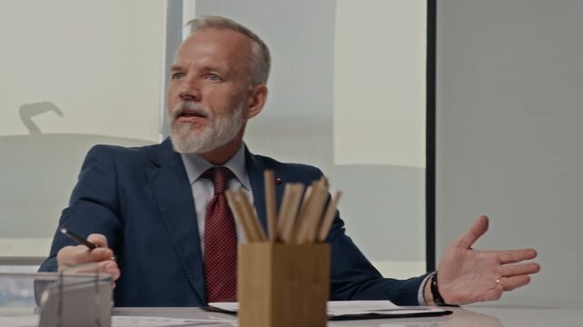 Handheld shot of business professionals attending corporate meeting, senior Caucasian businessman presenting oil transportation data. Perfect for energy sector marketing and corporate training