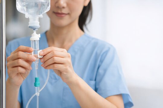Healthcare professional adjusting an intravenous IV drip line in a clinical setting