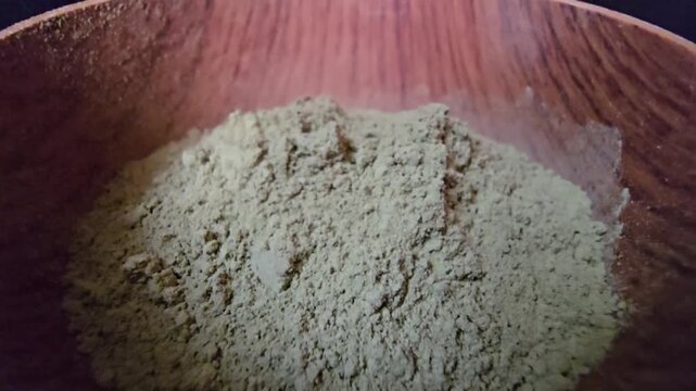 Close-up macro shot of Ziziphus spina-christi powder, commonly known as Sidr, inside a rustic wooden bowl.