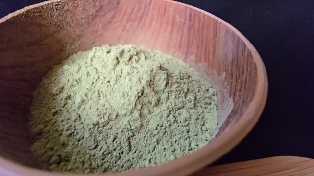 Fine powder of Ziziphus spina-christi leaves, also known as Sidr, in a wooden bowl.
