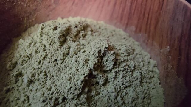 Close-up macro shot of Ziziphus spina-christi powder, commonly known as Sidr, inside a rustic wooden bowl.