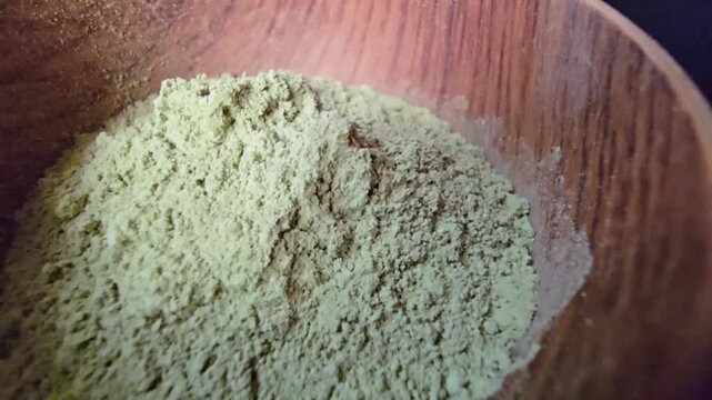 Close-up macro shot of Ziziphus spina-christi powder, commonly known as Sidr, inside a rustic wooden bowl.
