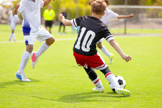 Youth Soccer Player Kicking Ball: Action Shot of Number 10 Striking Football on Field