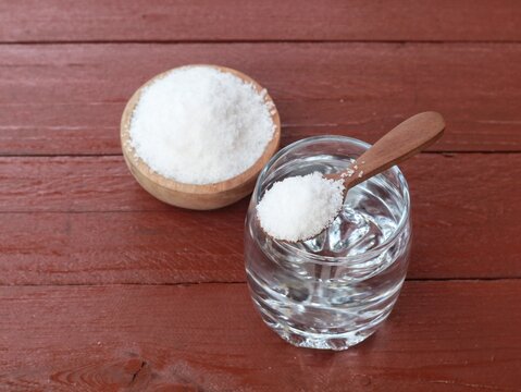 Salt water solution in glass with salt on wooden bowl on wooden table. Concept for dietary supplements, health drinks, and daily nutrition