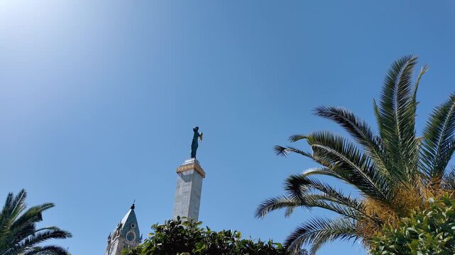 Beautiful view of the monument of medea with the golden fleece in europe square, batumi, georgia, framed by lush green palm trees against a clear blue sky on a sunny summer day