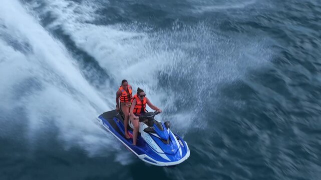Drone Close-Up Tracking Shot of Jet Ski on a mother and daughter riding a fast through the waters of Beau Vallon, Seychelles.