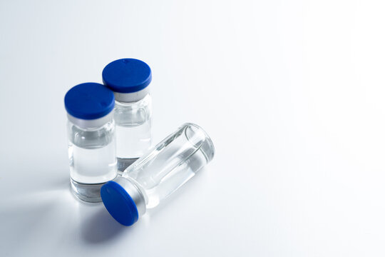 Medical vaccine vials with blue caps on clean white background