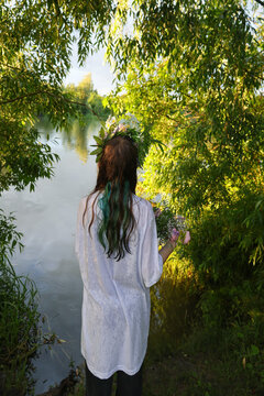 Young ault sitting near the lake water floating floral wreath with candle during Ivan Kupala