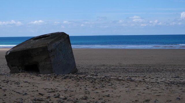 Sunny Normandy beach scene with remnants of concrete bunkers