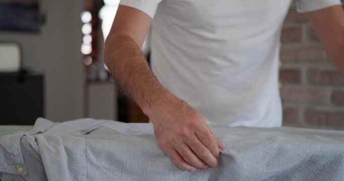 Home chore: Man ironing shirt with domestic appliance.