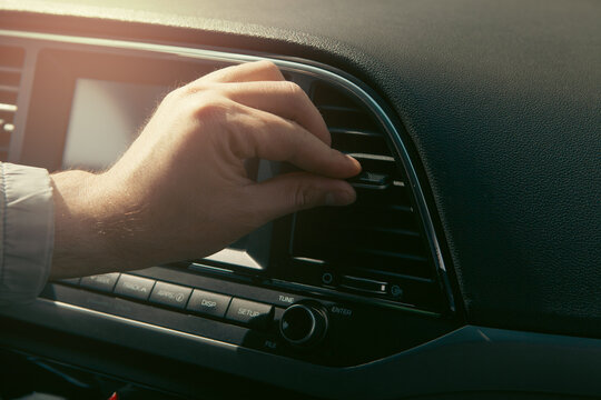 Close-up of a man's hand adjusting the air conditioner in a car