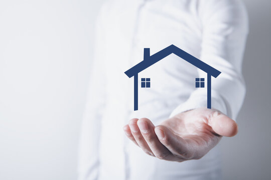 Hands holding a house symbol in front of a white background.