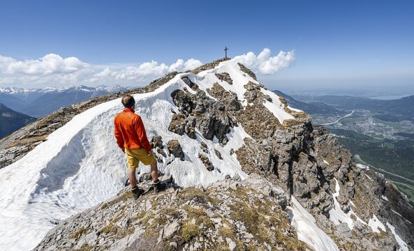 Hiker on the summit ridge of Thaneller with summit cross, mountain landscape, Lechtal Alps, Tyrol, Austria