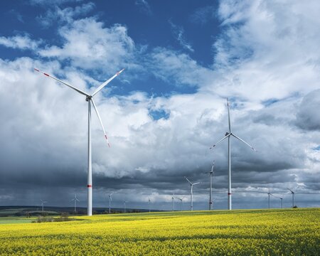 Wind turbines, wind turbines in rape field against blue sky with stormy clouds, thunderclouds, Thuringia, Germany
