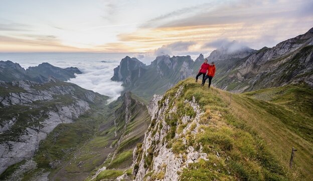 View over S&auml;ntis mountains into the valley of Meglisalp at sunrise, couple, mountaineers at Rotsteinpass, high fog in the valley, S&auml;ntis, Appenzell Ausserrhoden, Appenzell Alps, Switzerland