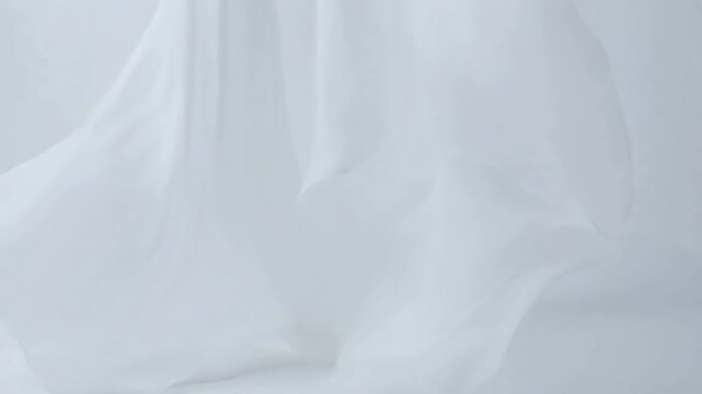 White sheer fabric gently flowing and draping in soft motion