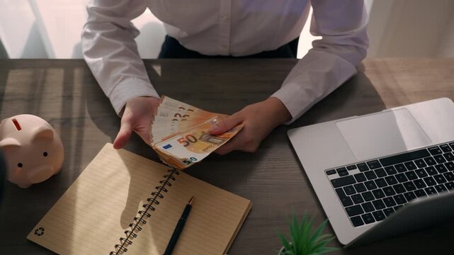 Businesswoman's hands meticulously counting thick stack of euro banknotes over wooden desk, symbolizing concepts like salary, profit, investment, and financial success