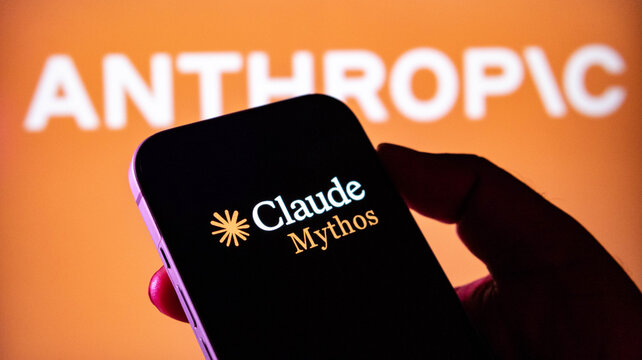 Hand holding a smartphone displaying the claude mythos logo in front of an anthropic brand background