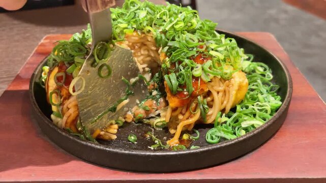 日本のお好み焼き。青ネギと焼きそば麺がたっぷり入った広島お好み焼き。コテでカットする断面動画。