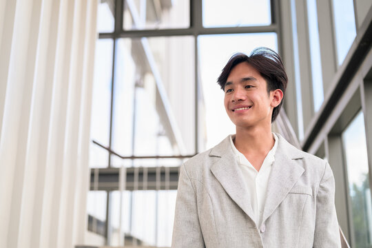 Smiling young nonbinary Thai business professional looking away on office stairs