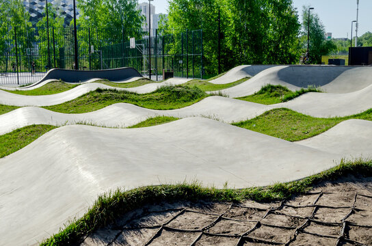 concrete pump tracks are suitable for bicycles, scooters, skateboards, longboards, roller skates. teens enjoy riding on this track. modern track provides active sport and rest in park area outdoors.